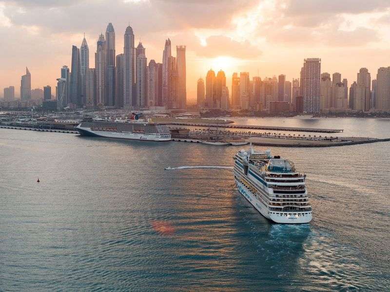 Dubai skyline at sunset with a Dhow Cruise sailing along the creek.