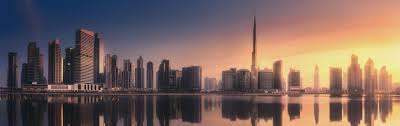 Dubai skyline at sunset with a Dhow Cruise sailing along the creek.