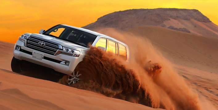 Image depicting a 4x4 vehicle traversing the mesmerizing red dunes of the Dubai desert during the Red Dune Bashing adventure with Dubai Dhow Cruises.
